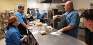 A group of people in the kitchen preparing food.