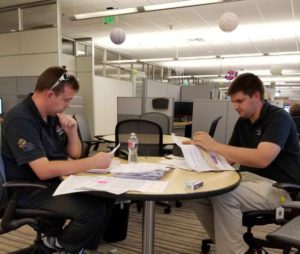 Two men sitting at a table working on papers.